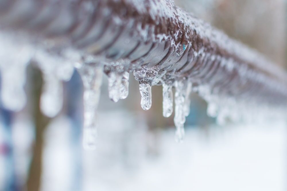 A frozen water pipe covered in ice and frost during a winter cold snap.