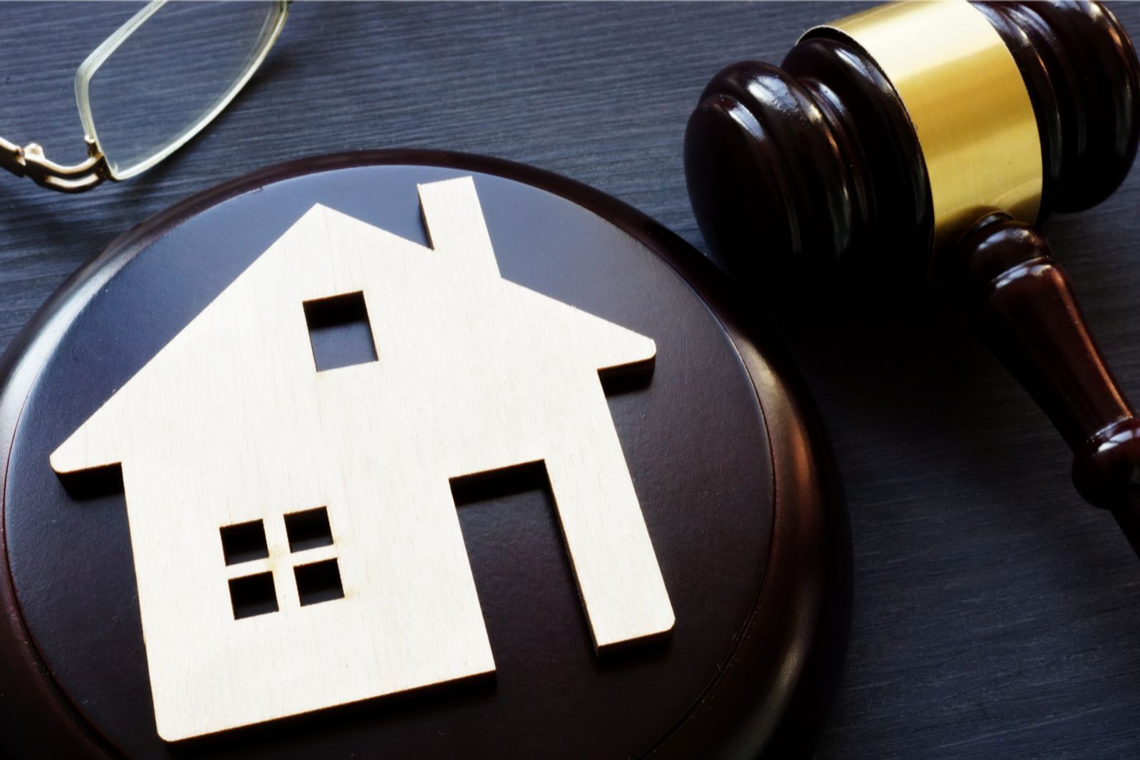 Wooden house model with a judge's gavel on a desk, representing Ohio landlord-tenant laws and rental regulations.