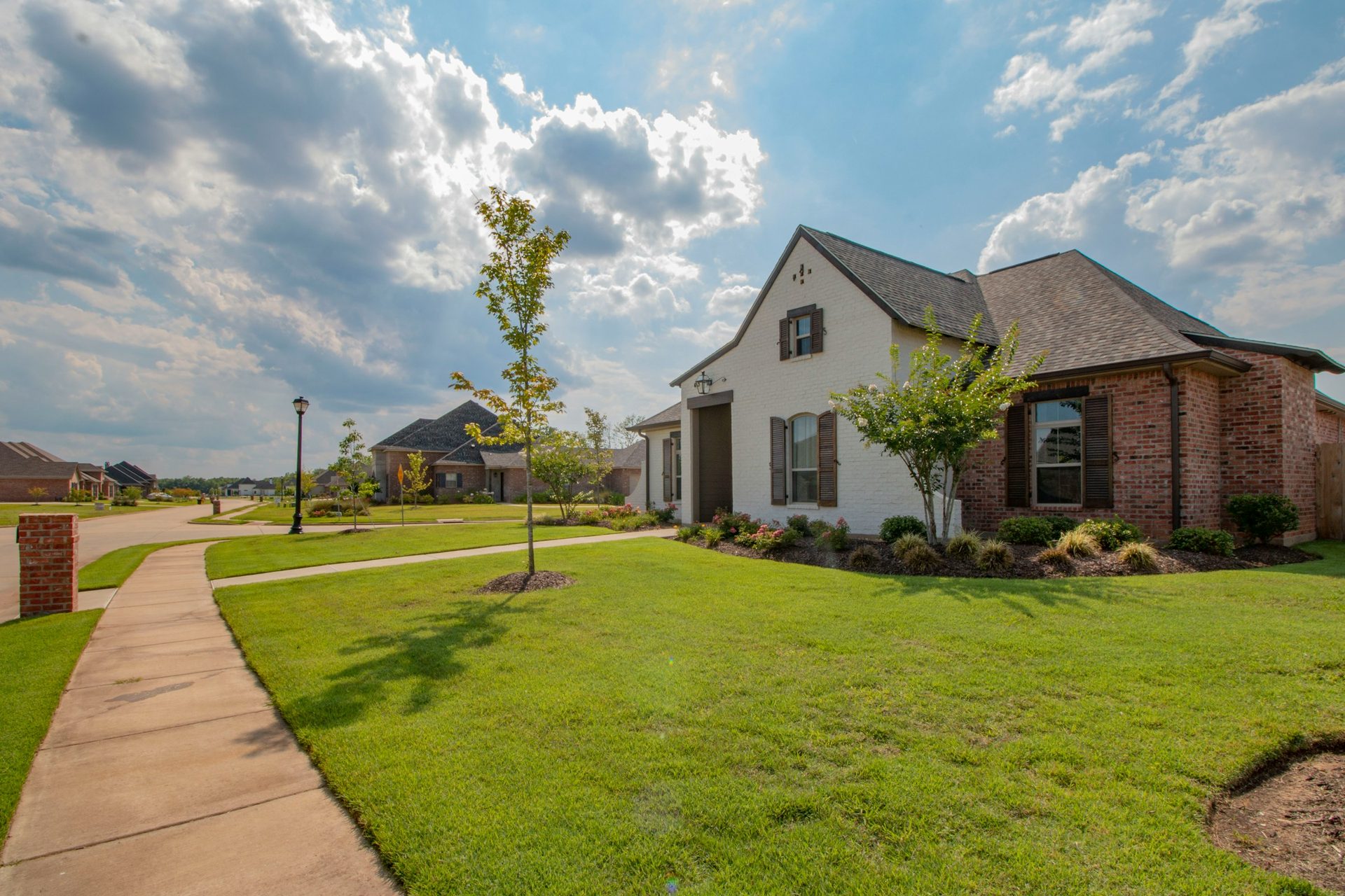 Suburban street of brick homes, sidewalks, and manicured lawns in an HOA-managed community