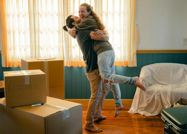couple hugging in a living room full of moving boxes
