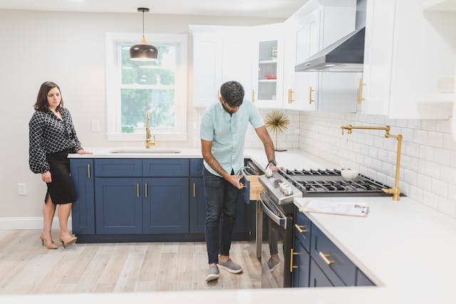 realtor showing a house while a buyer inspects the drawers in the kitchen