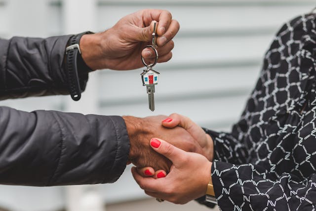 people shaking hands as they hand over house keys