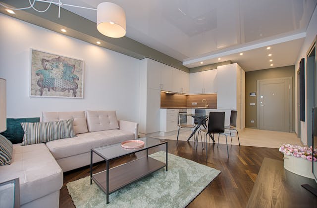 an apartment living room and kitchen with white walls and light wood accents