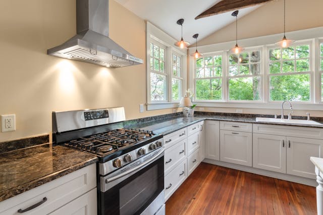 a beige kitchen with white cabinets and black counters