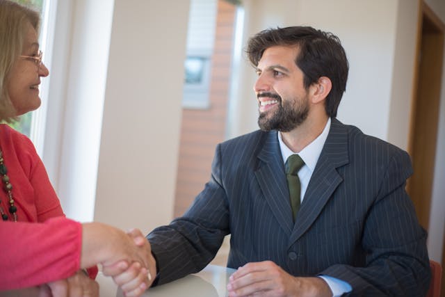 a property manager in a dark suit shaking hands with someone in pink