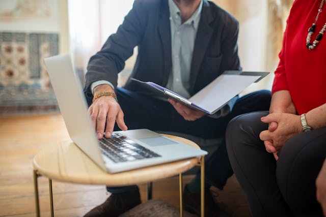 two people looking at a laptop while one holds a folder