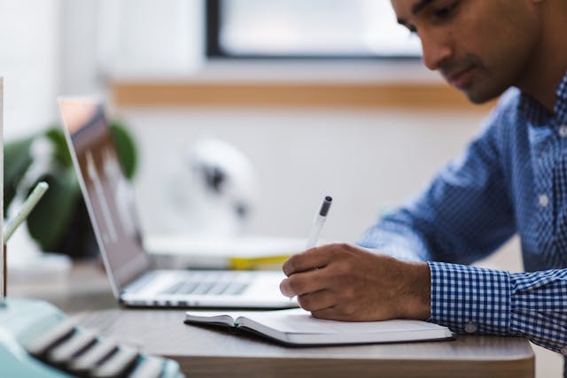 person working on a laptop and taking notes