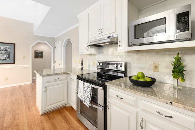 a beige kitchen with white cabinets and modern appliances