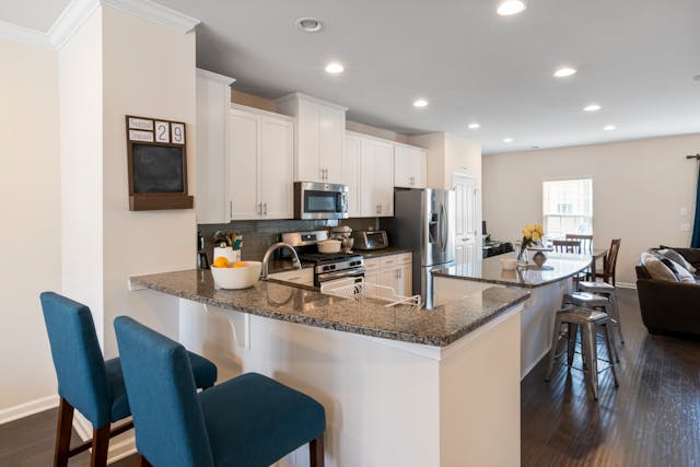 a white kitchen with dark counters and modern appliances