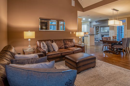 a beige living room with dark brown leather couches