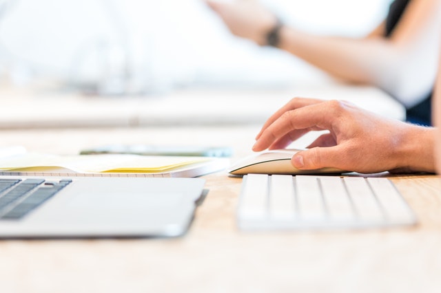 a hand on a mouse while working on a computer