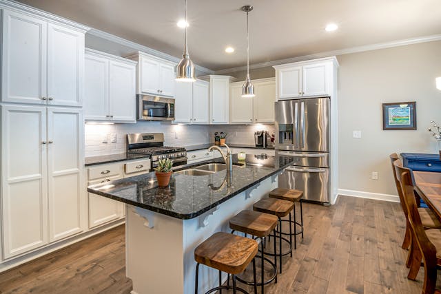 a kitchen with white cabinets and dark counters