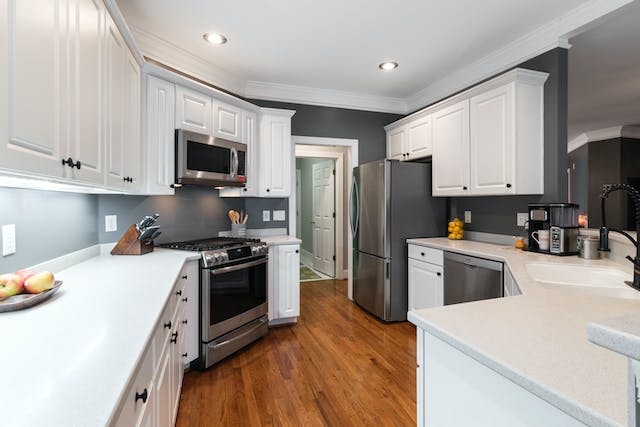 a grey kitchen with white cabinets and counters