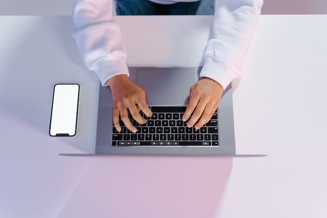 birds eye view of someone typing on a laptop at white desk