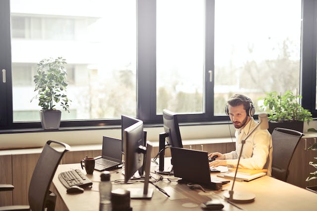 employee working alone at shared desk spaces with a total for four computer monitors