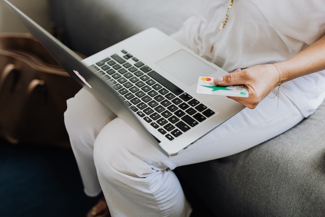 person holding a credit card and their laptop to make an online payment