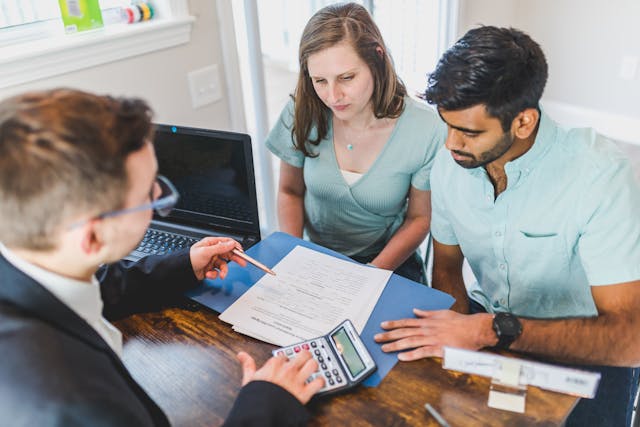 a real estate expert meeting with two people and going over contracts