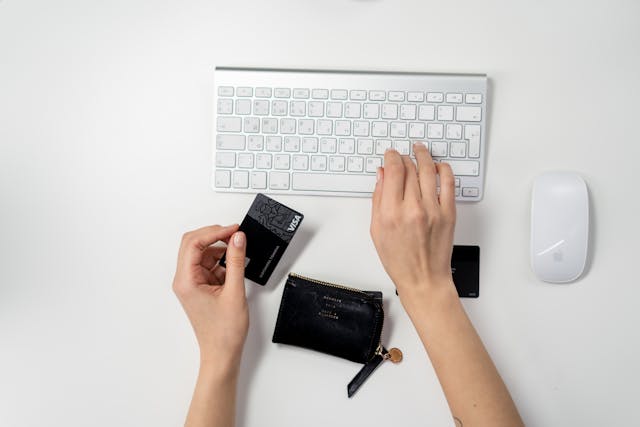 A hand holding a credit card to make an online payment