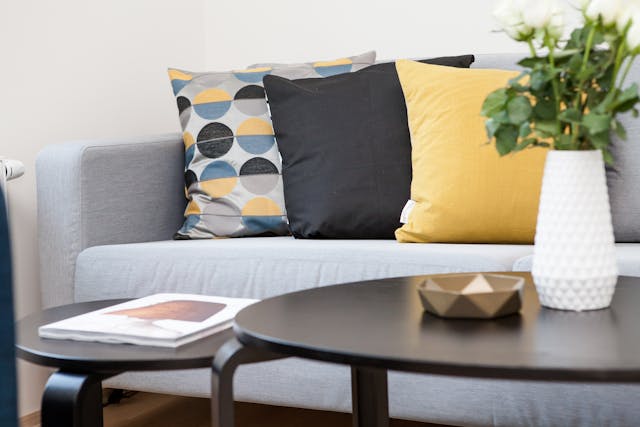 a grey couch with yellow and blue pillows on it