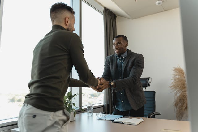 two people shaking hands across a desk