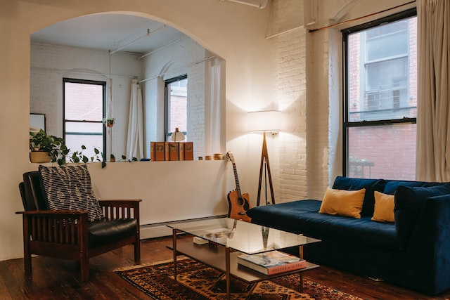 living room with white brick walls, a blue couch and a large lamp in the corner