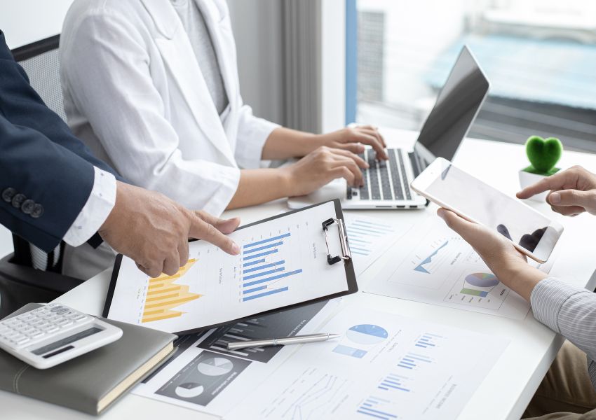 people looking over stands and graphs on documents that symbolize investment returns
