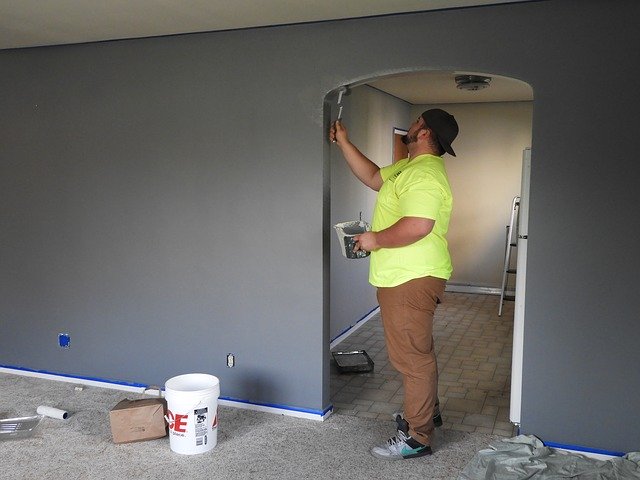 A Contractor Touching Up Paint On A Wall