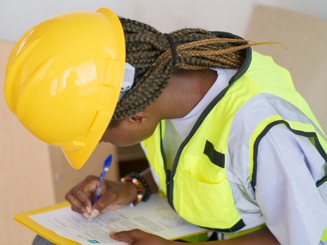 a person in yellow hard hat filling out an inspection report