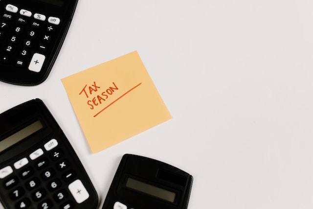 An orange sticky note with the words tax seasons written in red