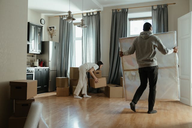 a couple moving boxes and art into their new rental property