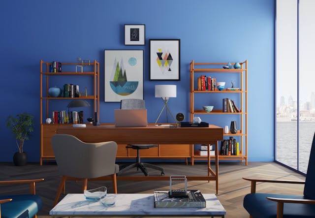 a home office with a blue accent wall and dark wood furniture