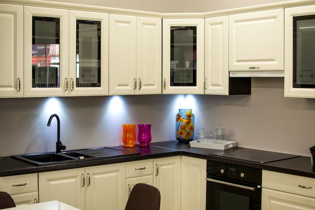 a kitchen with dark granite counters and white cabinets with built in lighting
