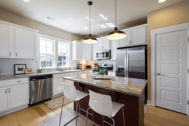 a kitchen with beige walls, white cabinets, and granite counters