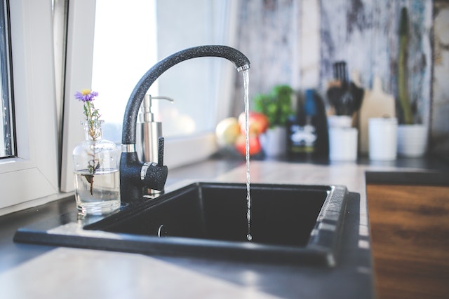black kitchen sink and faucet with running water coming out of it